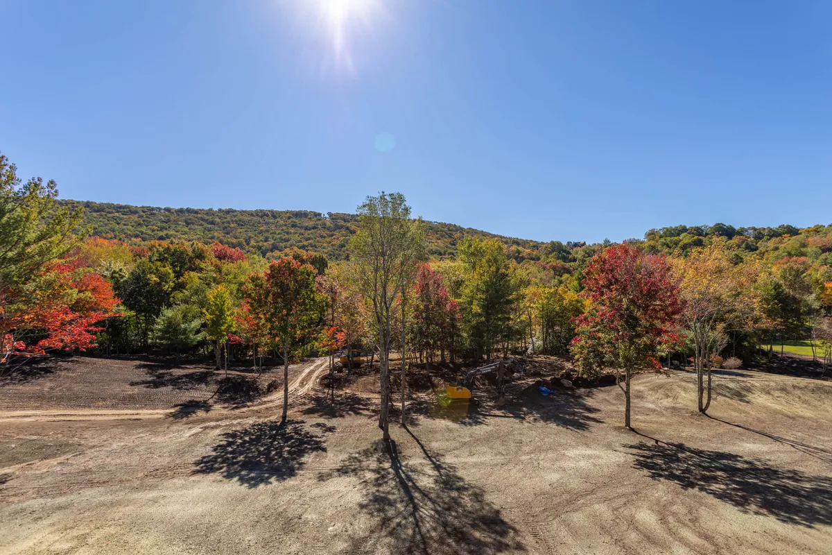 A panoramic view of rolling hills blanketed in vibrant autumn colors, with sunlight casting a warm glow through the trees. The scene invites exploration with its serene trails and natural splendor, perfect for hiking, nature walks, or quiet moments together.